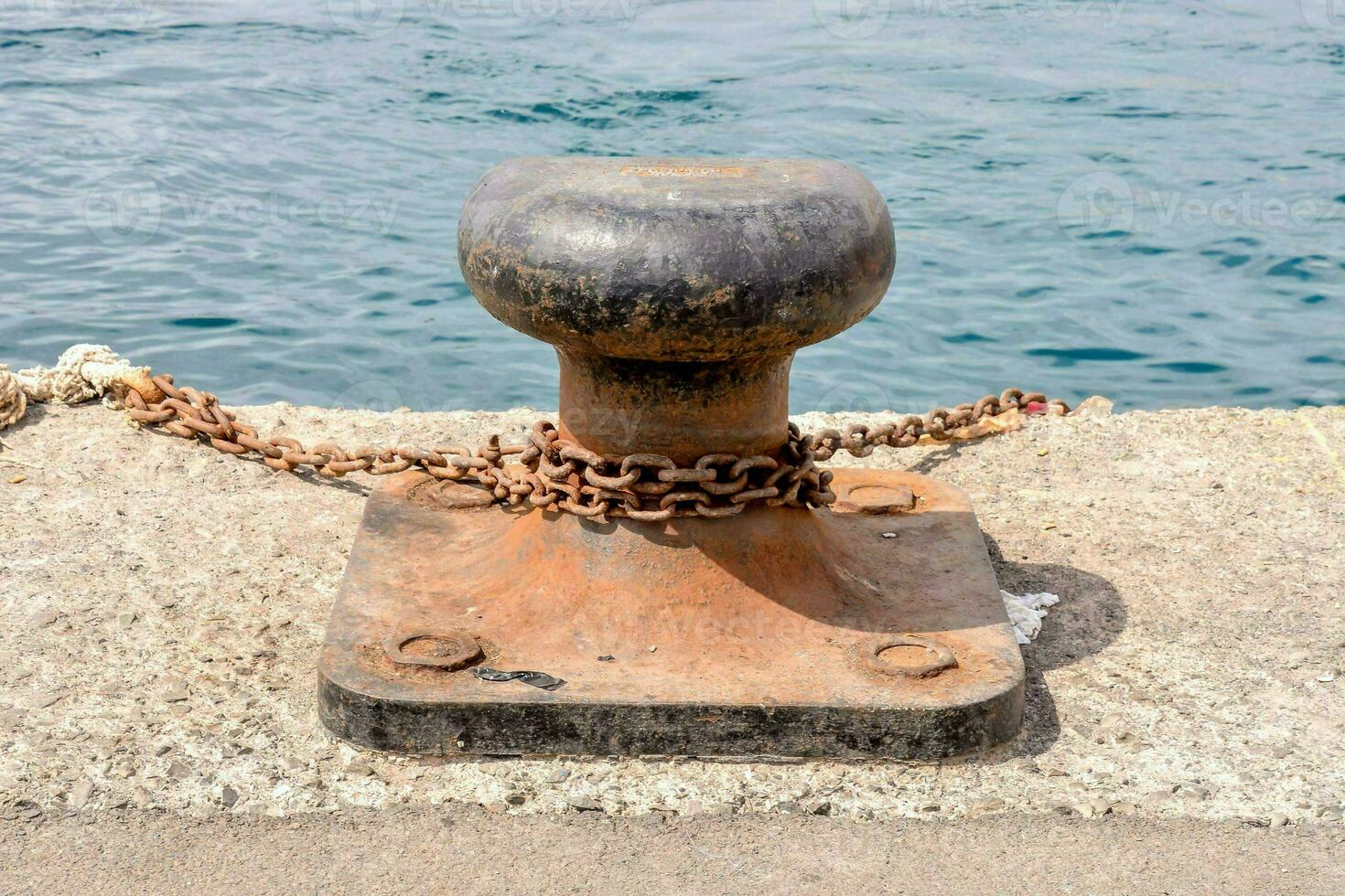 a rusty metal post with a chain attached to it photo