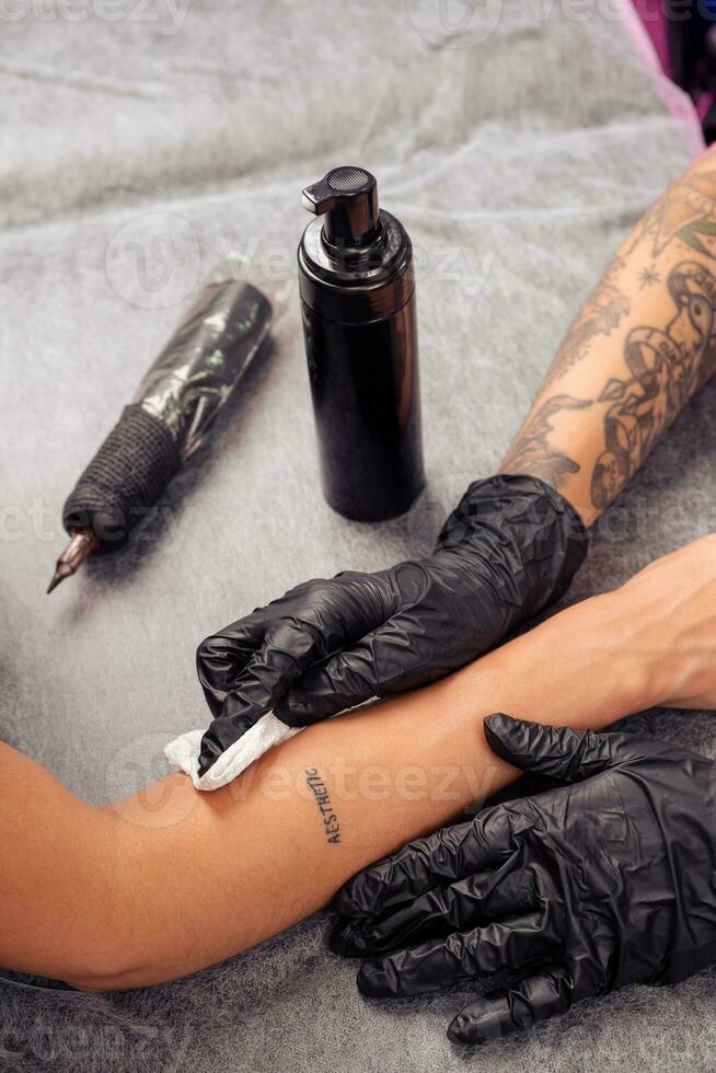 Tattoo artist cleansing tattooed skin with antibacterial foam photo