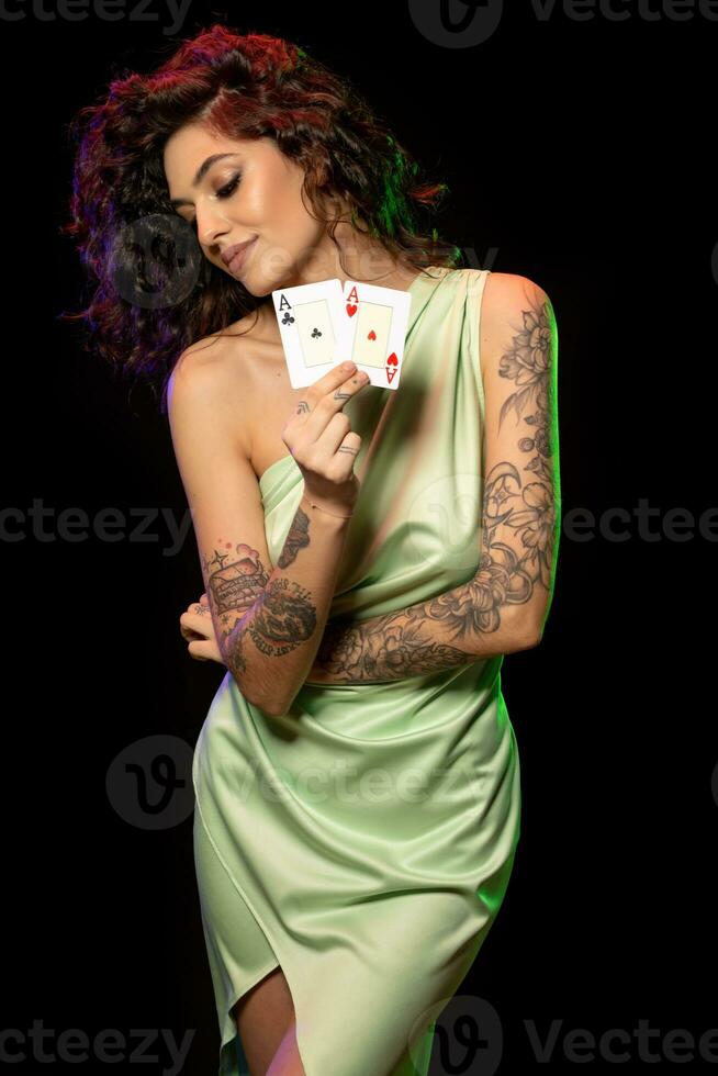 Smiling young woman with tattoo on arms showing pair of aces photo