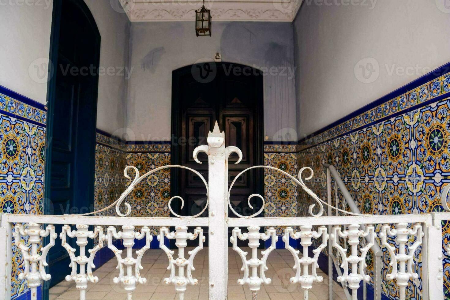a white wrought iron fence in front of a tiled entrance photo