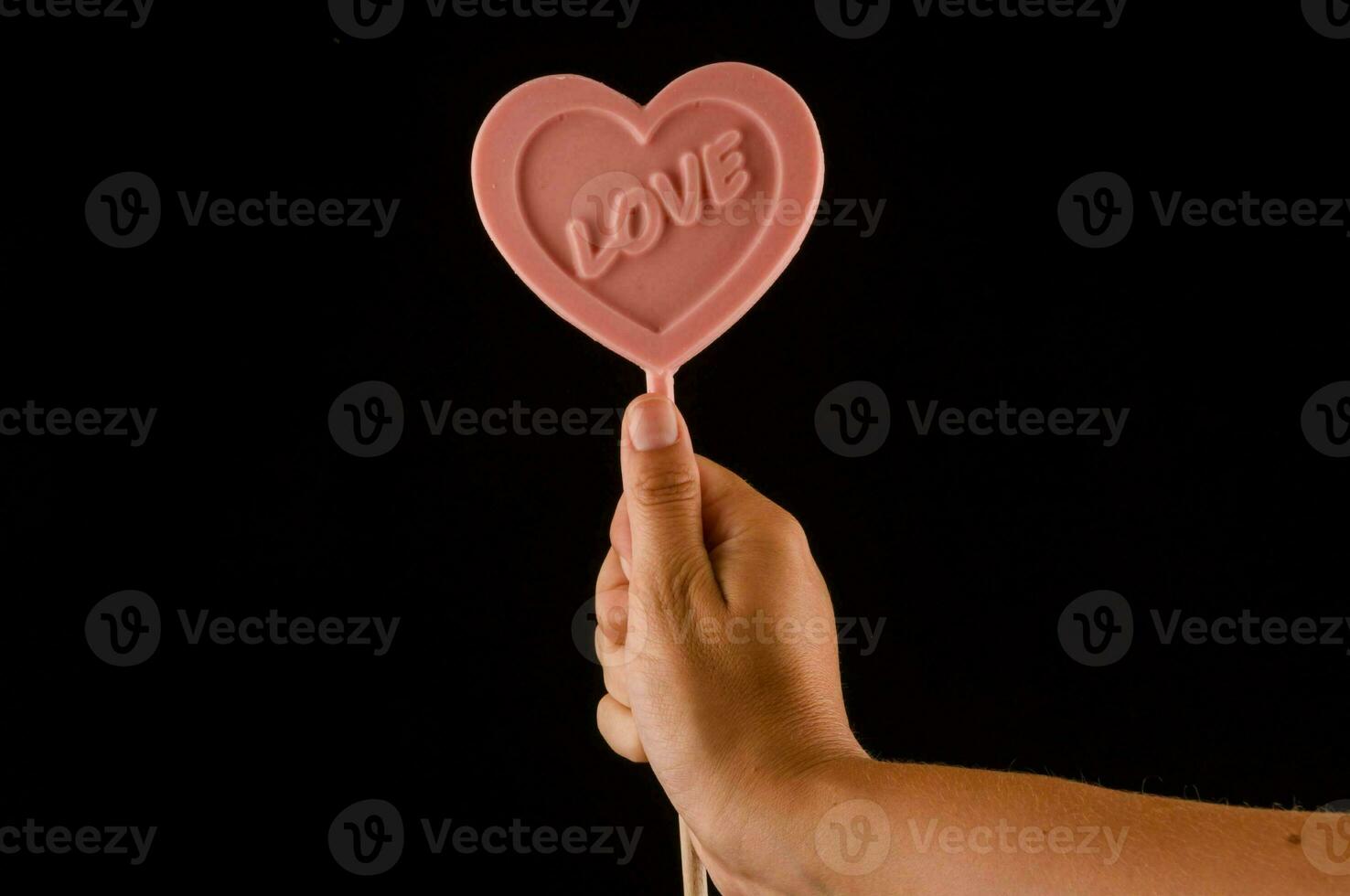 a person holding a pink heart shaped lollipop photo