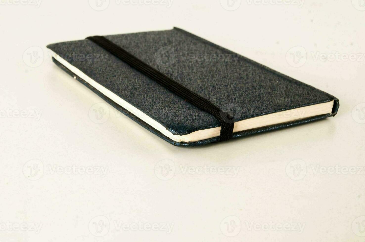 a notebook with a black cover sitting on a white surface photo