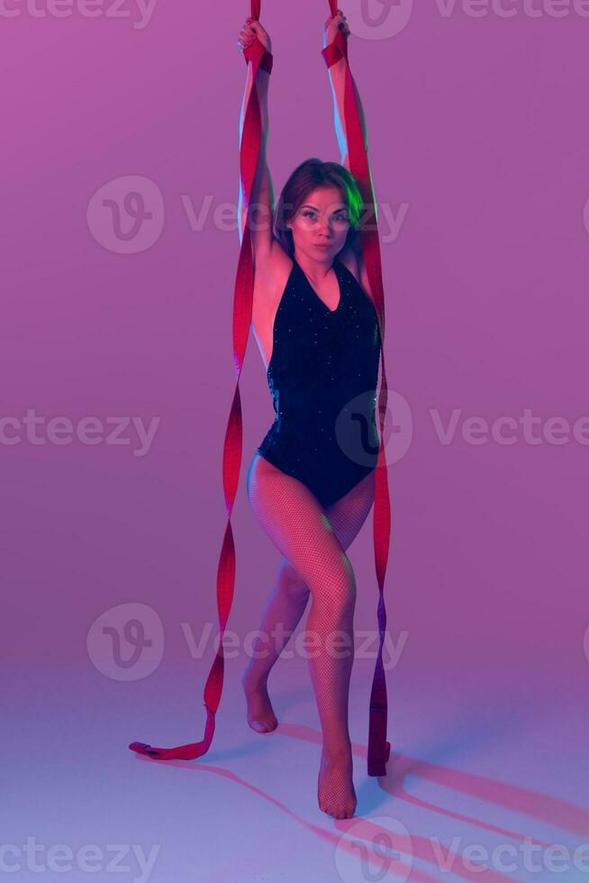 Beautiful girl in a black swimsuit is performing an acrobatic elements in studio. photo