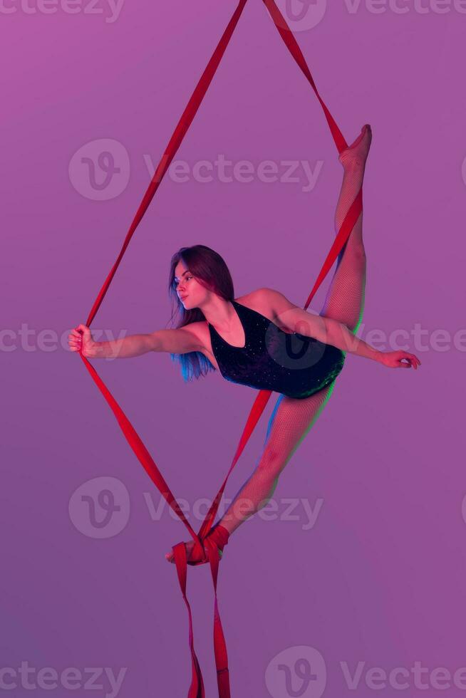 Beautiful girl in a black swimsuit is performing an acrobatic elements in studio. photo