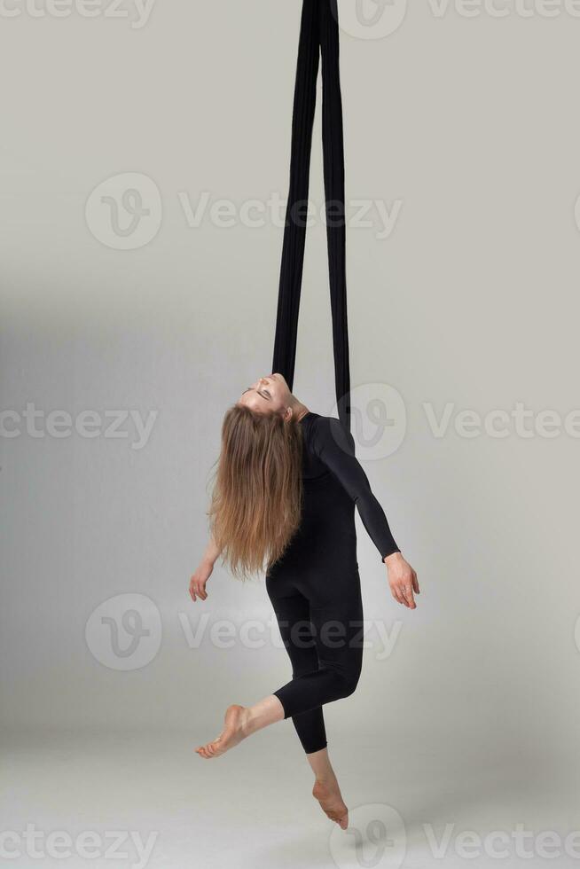 hermosa niña en un negro deporte traje es ejecutando un acrobático elementos en un estudio. foto