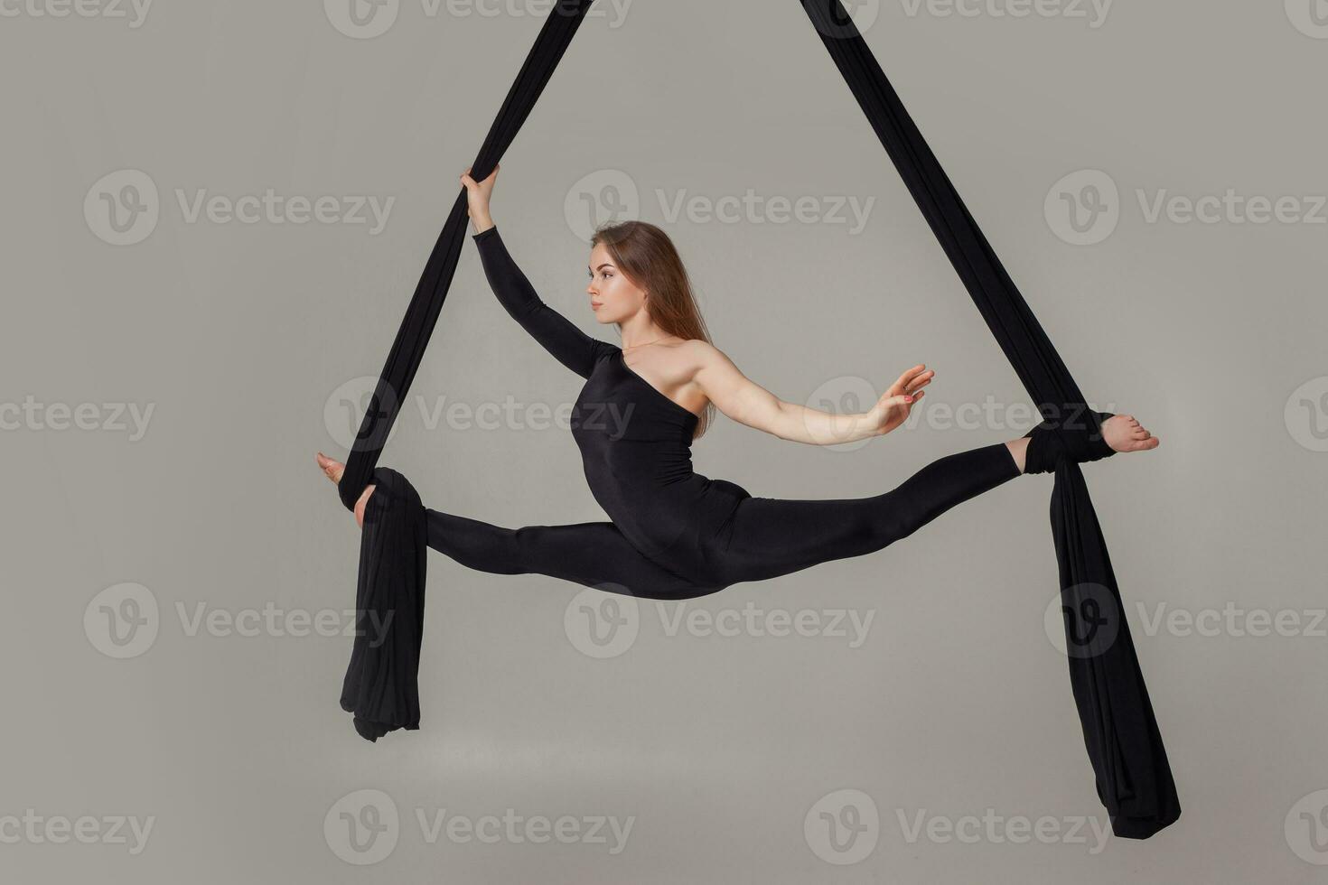 hermosa niña en un negro deporte traje es ejecutando un acrobático elementos en un estudio. foto
