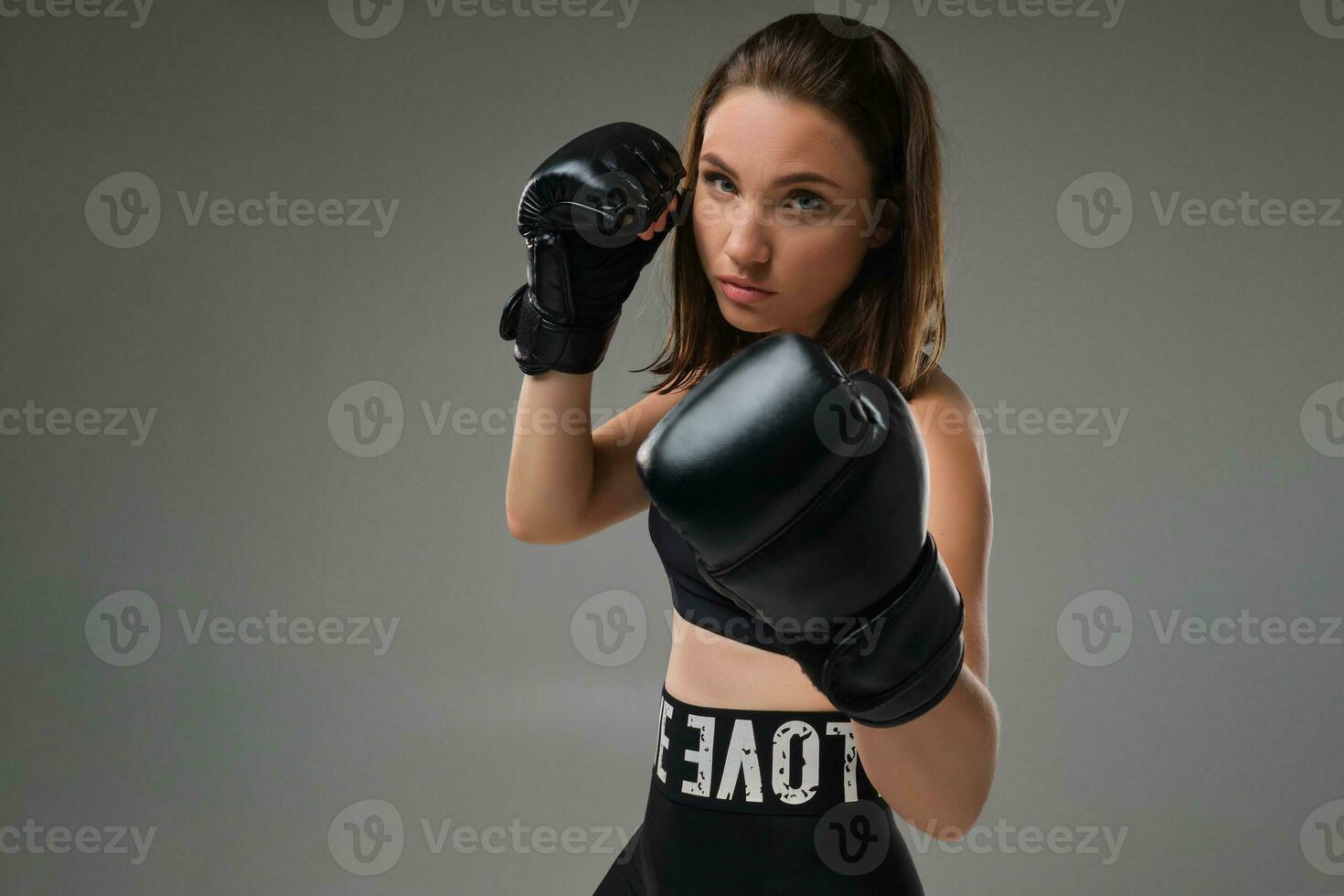 Athletic woman in boxing gloves is practicing karate in studio. photo