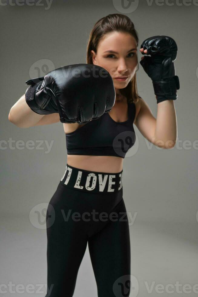 Athletic woman in boxing gloves is practicing karate in studio. photo