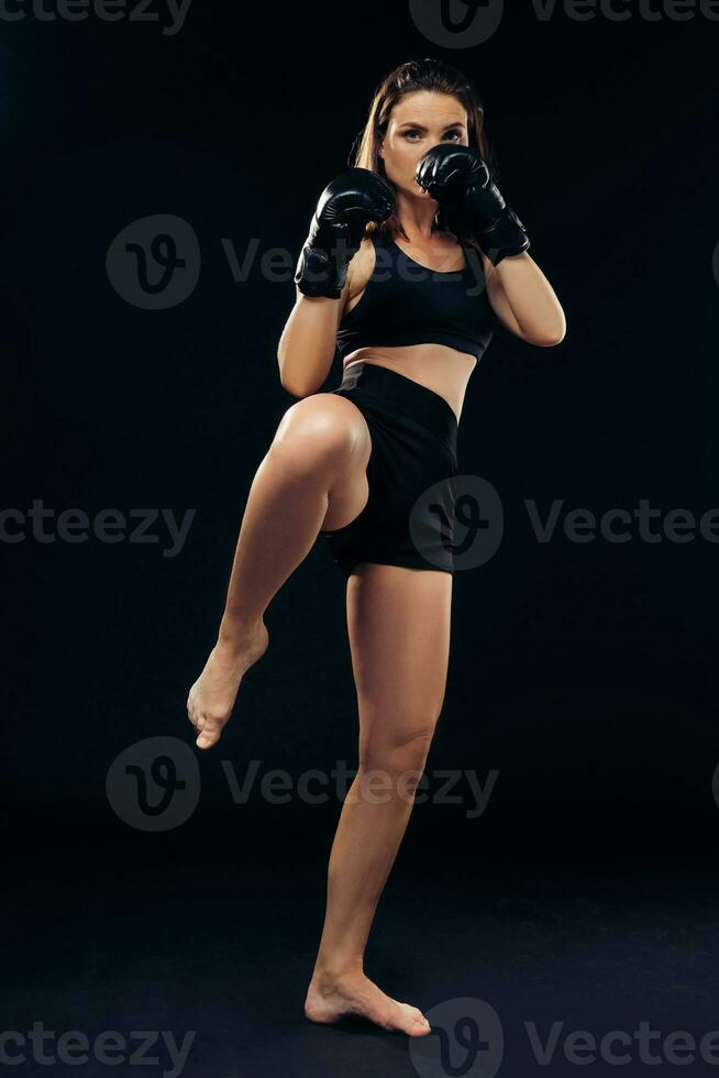 atlético mujer en boxeo guantes es practicando kárate en estudio. foto