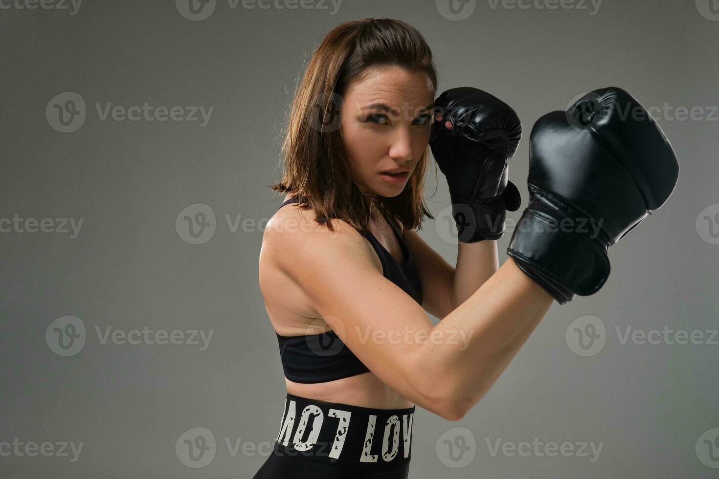 Athletic woman in boxing gloves is practicing karate in studio. photo