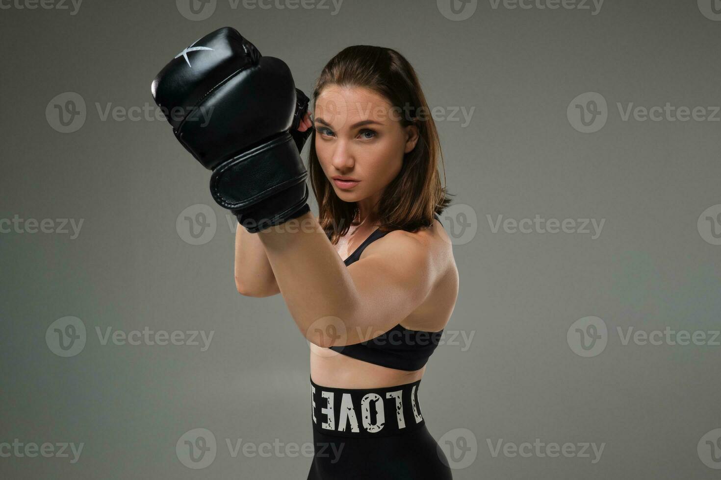 Athletic woman in boxing gloves is practicing karate in studio. photo