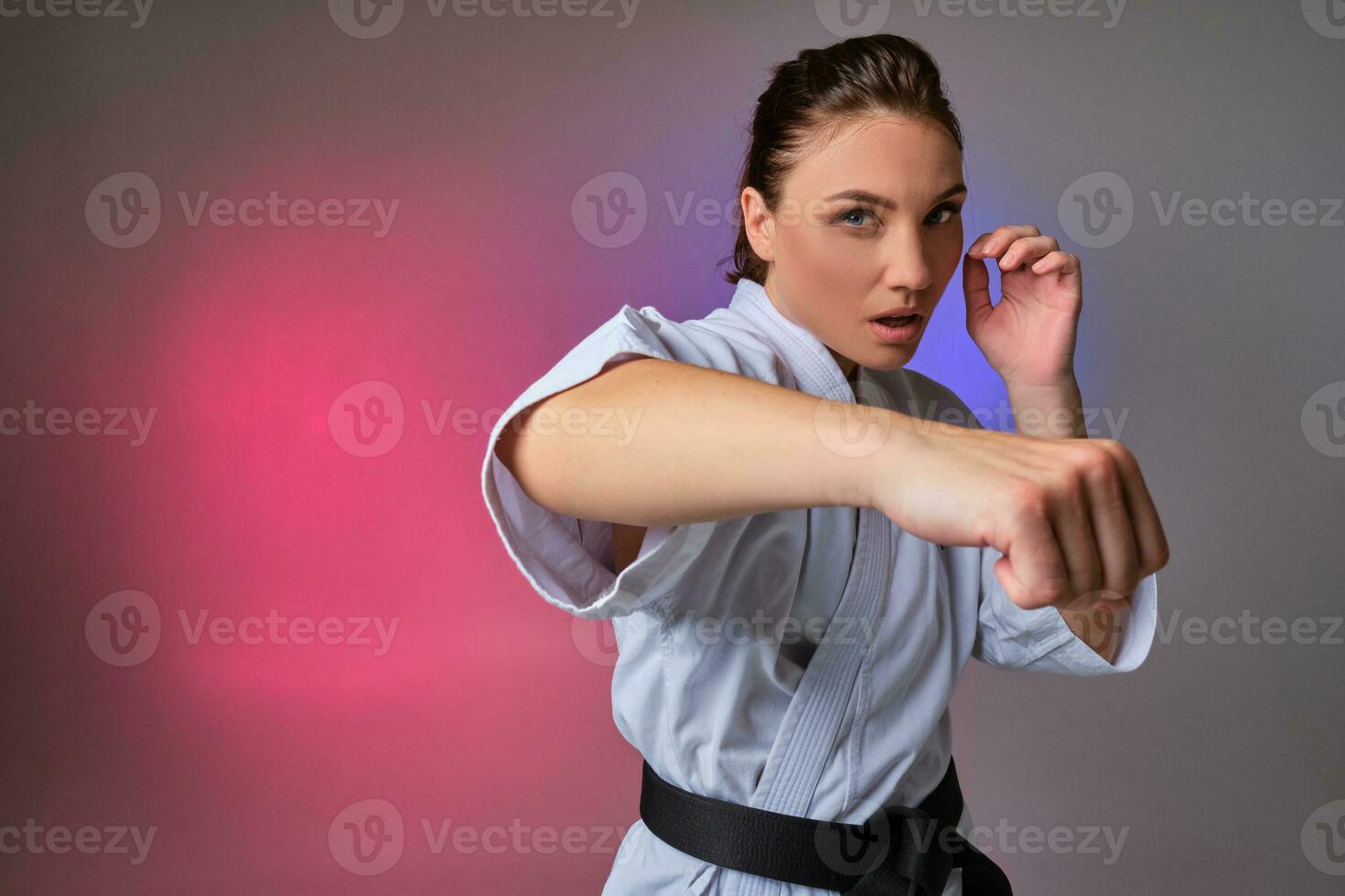 atlético mujer en tradicional kimono es practicando kárate en estudio. foto