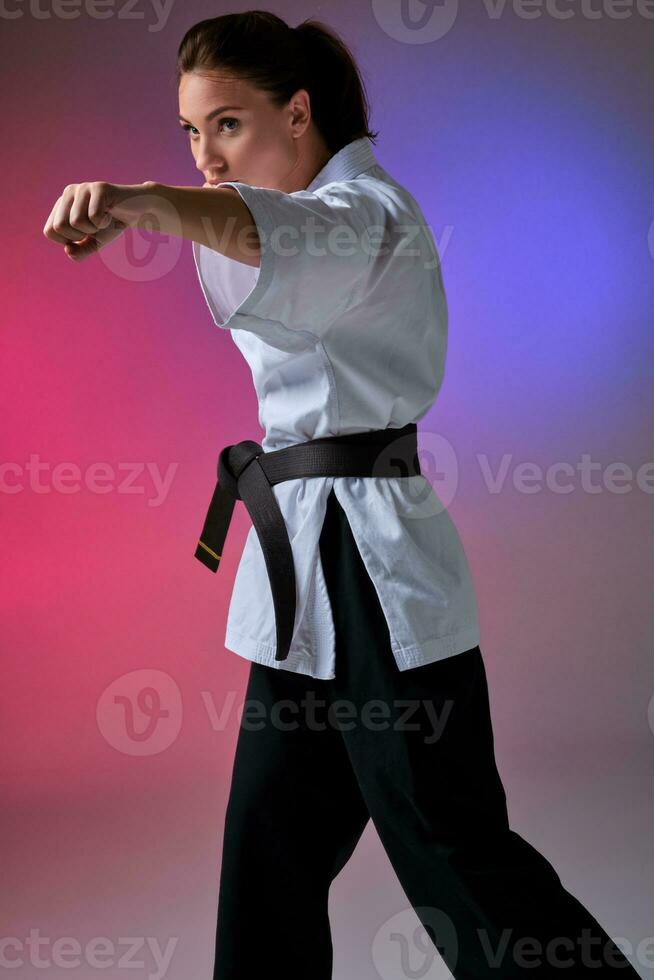 Athletic woman in traditional kimono is practicing karate in studio. photo