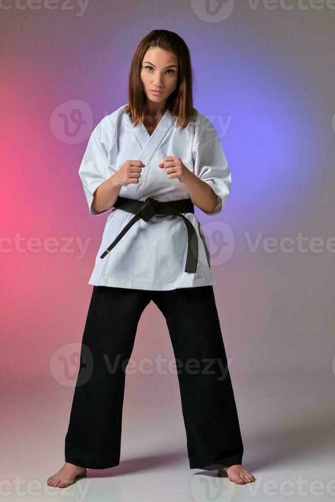 Athletic woman in traditional kimono is practicing karate in studio. photo