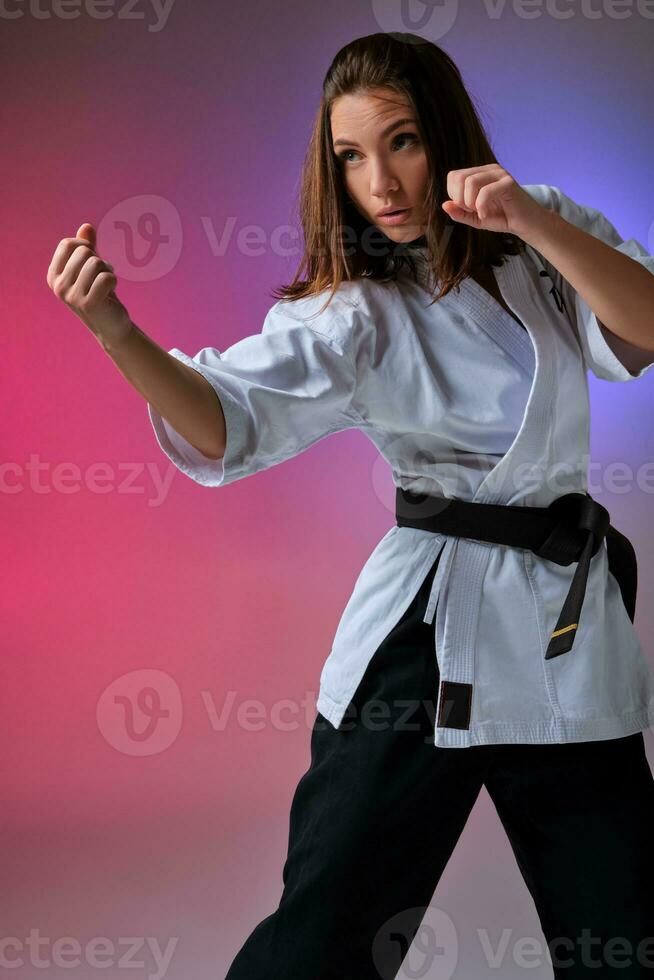 Athletic woman in traditional kimono is practicing karate in studio. photo