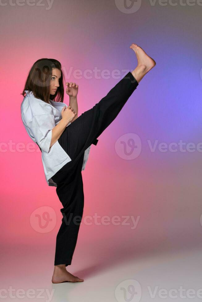 Athletic woman in traditional kimono is practicing karate in studio. photo