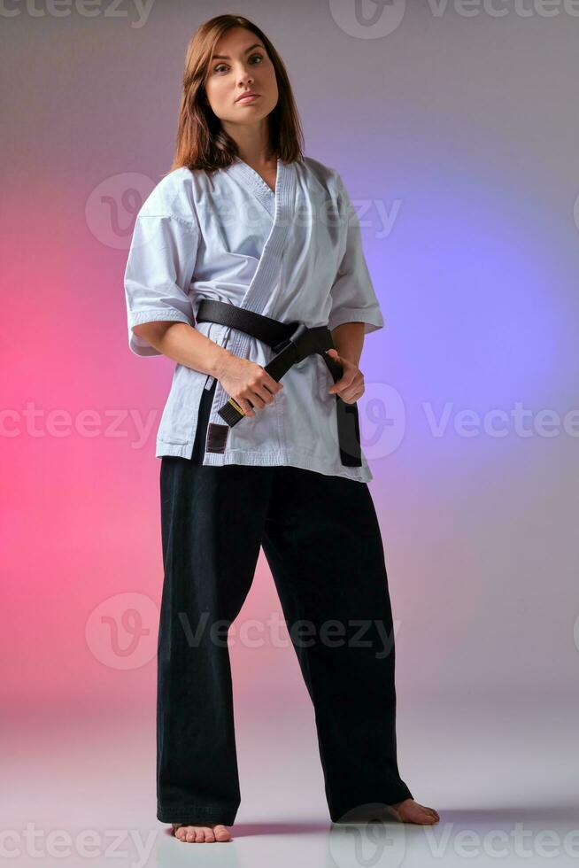 Athletic woman in traditional kimono is practicing karate in studio. photo