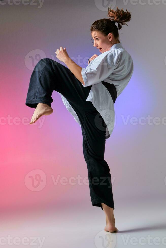 Athletic woman in traditional kimono is practicing karate in studio. photo