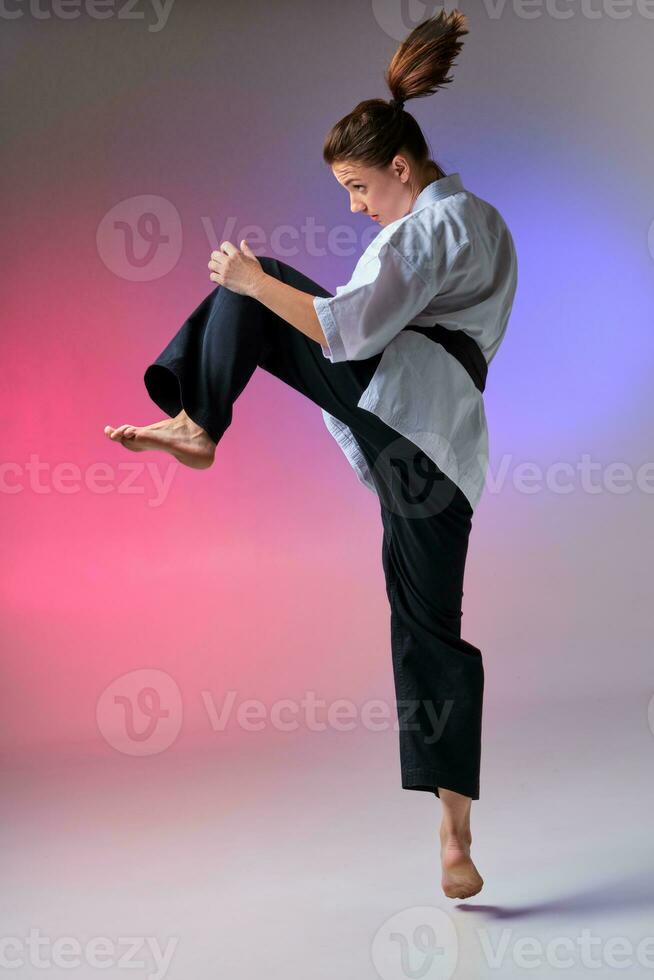 Athletic woman in traditional kimono is practicing karate in studio. photo