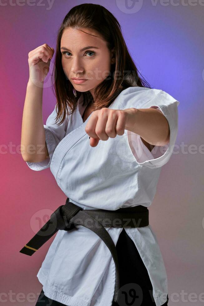 Athletic woman in traditional kimono is practicing karate in studio. photo