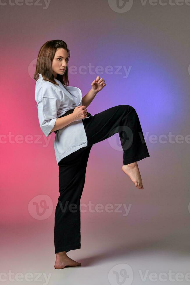 Athletic woman in traditional kimono is practicing karate in studio. photo