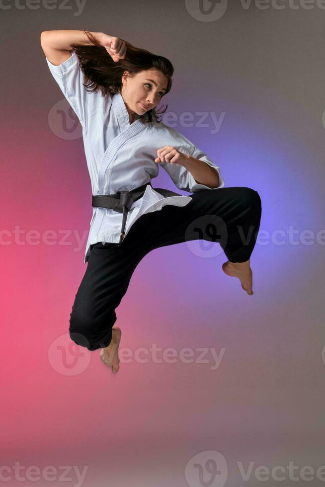 Athletic woman in traditional kimono is practicing karate in studio. photo