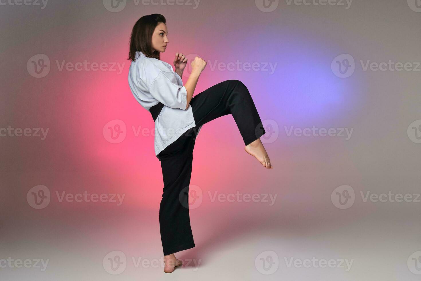 Athletic woman in traditional kimono is practicing karate in studio. photo