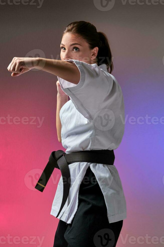 Athletic woman in traditional kimono is practicing karate in studio. photo