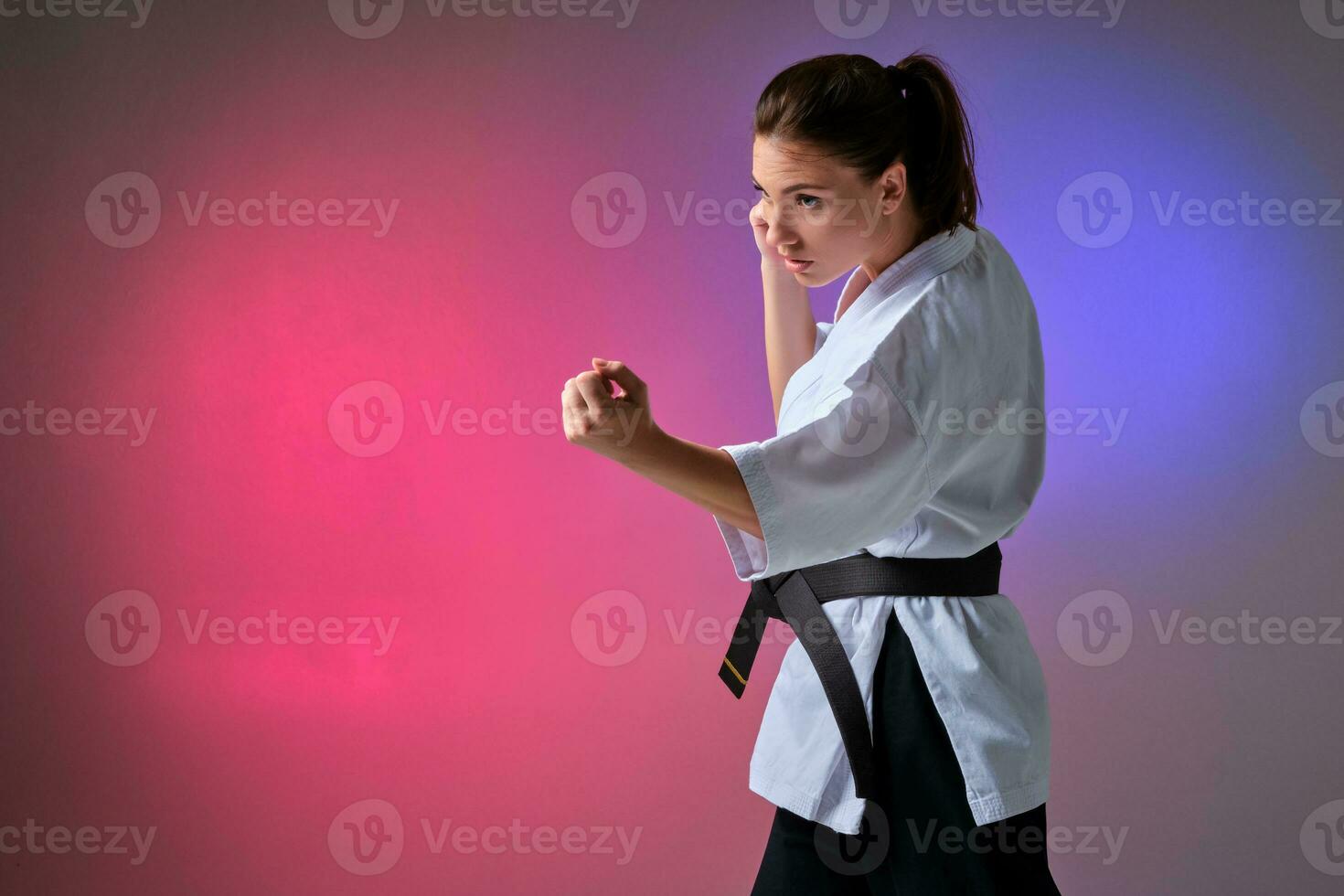 Athletic woman in traditional kimono is practicing karate in studio. photo