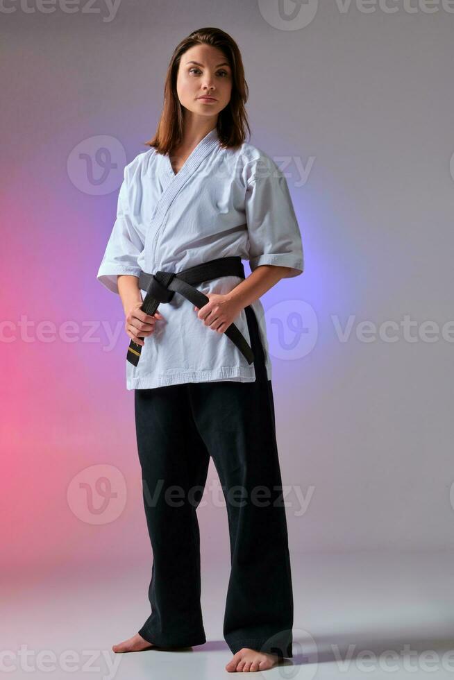 Athletic woman in traditional kimono is practicing karate in studio. photo