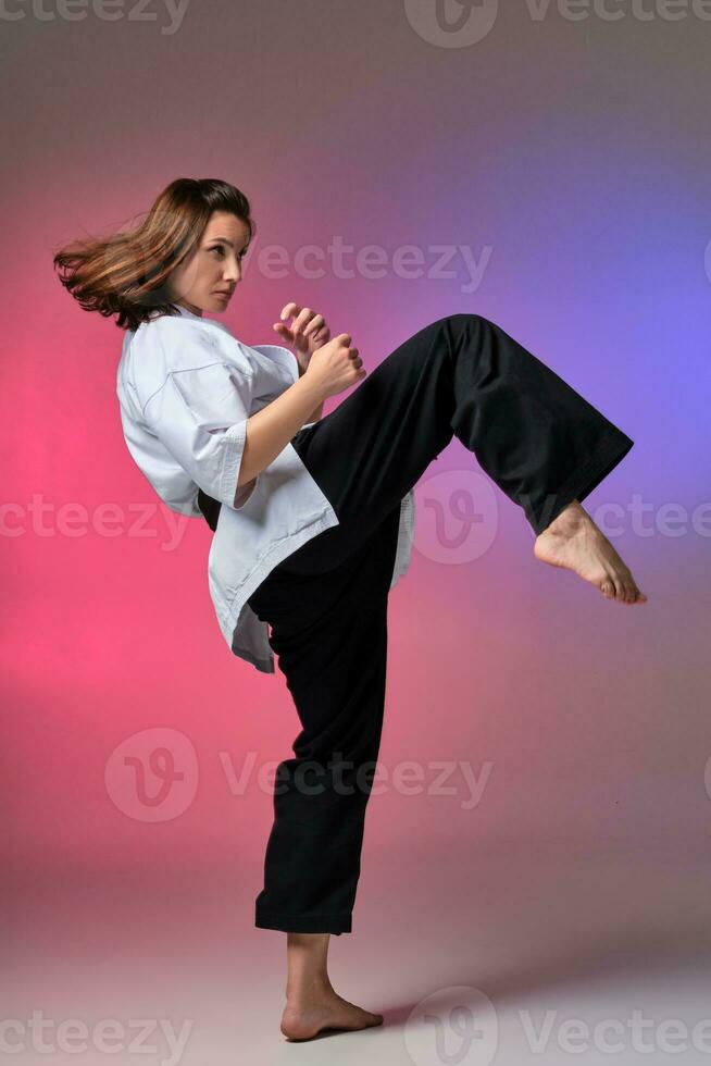 Athletic woman in traditional kimono is practicing karate in studio. photo