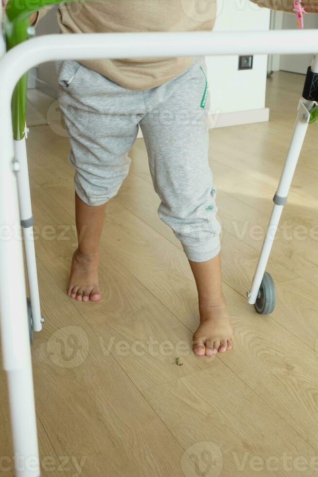 child with walking frame and knee orthosis at home photo