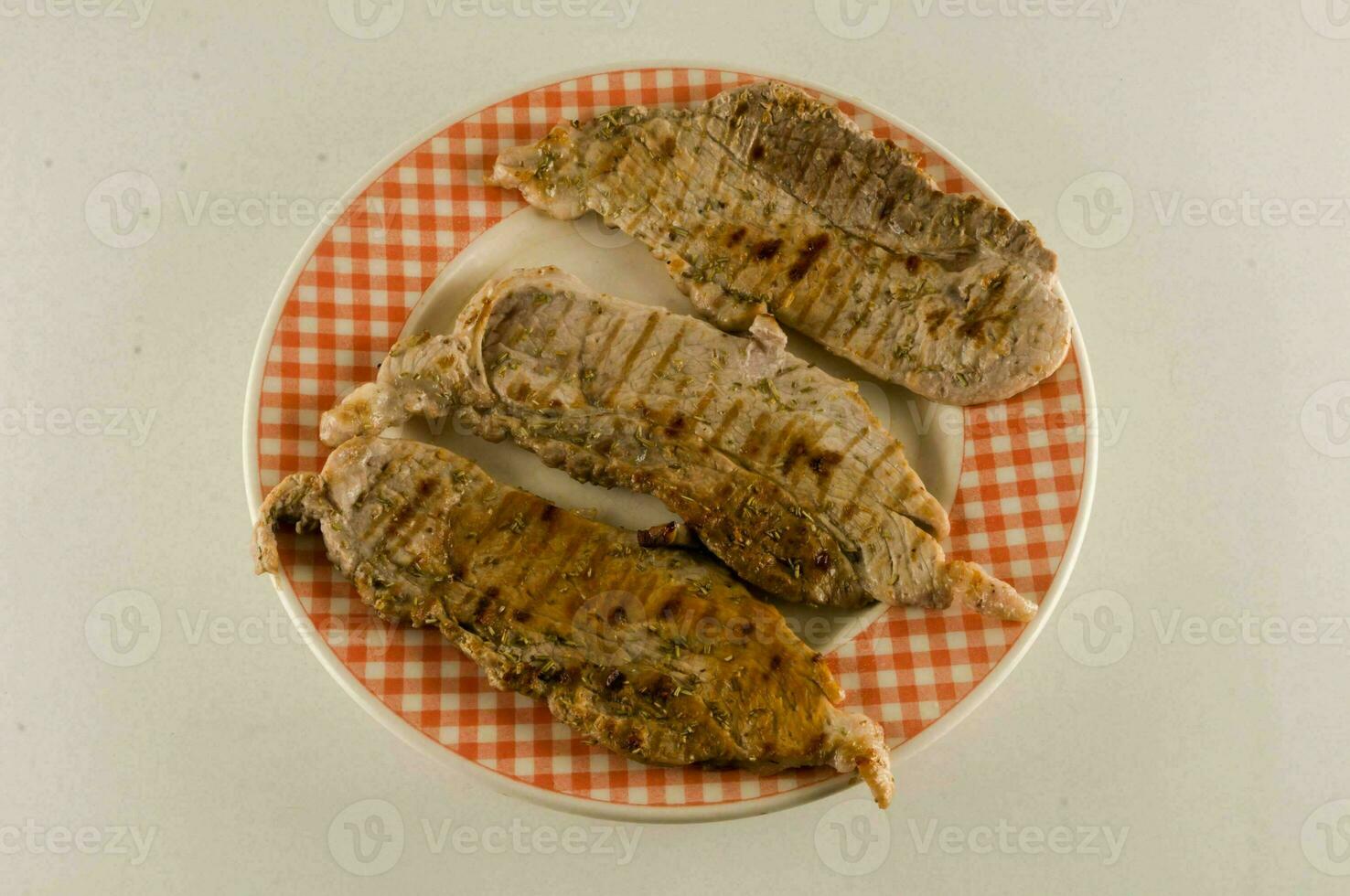 three pieces of meat on a plate with a checkered pattern photo