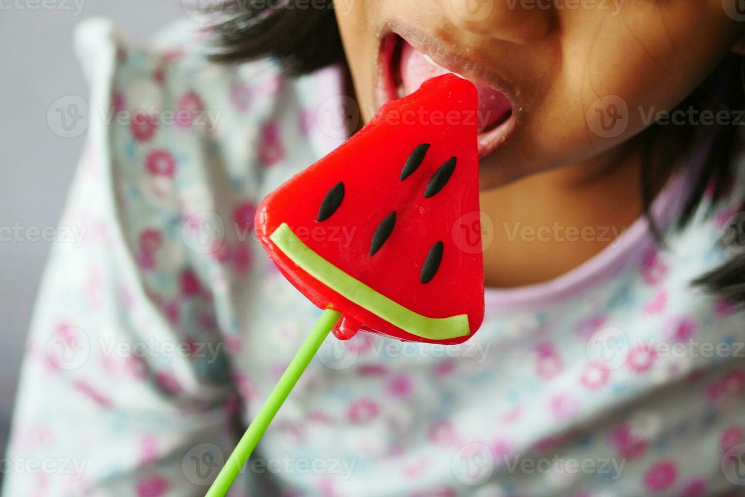 child is licking colorful candy on stick, photo