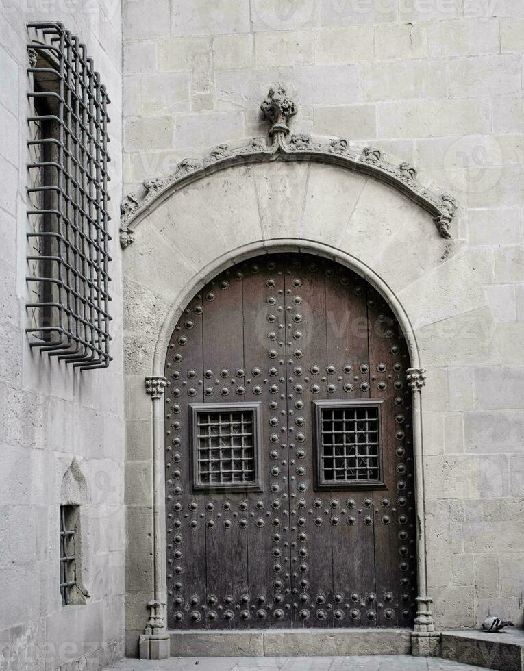 Wooden door with iron fittings in Gothic Quarter street in Catalonia. A medieval door of wood in a stone wall. photo