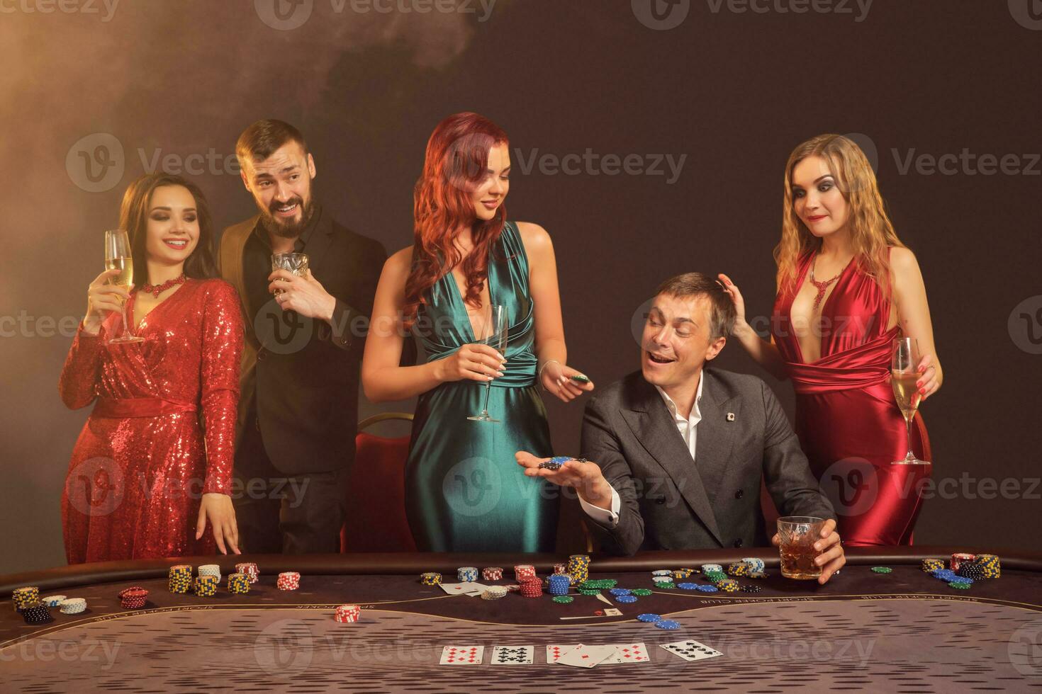 Group of a young wealthy friends are playing poker at a casino. photo