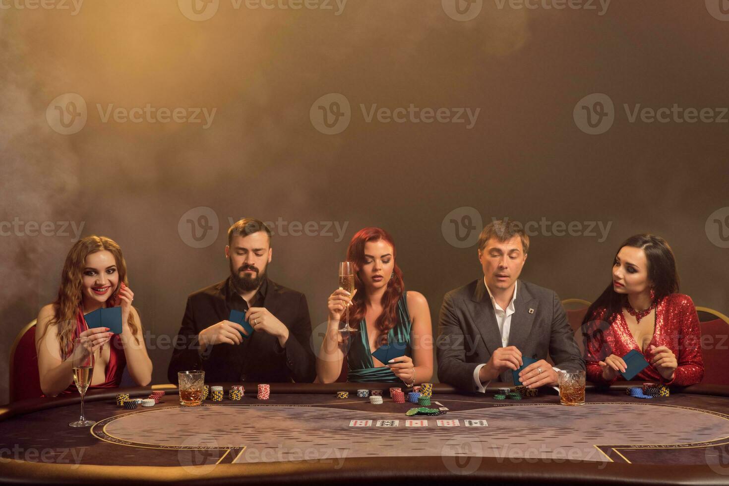 Group of a young wealthy friends are playing poker at a casino. photo