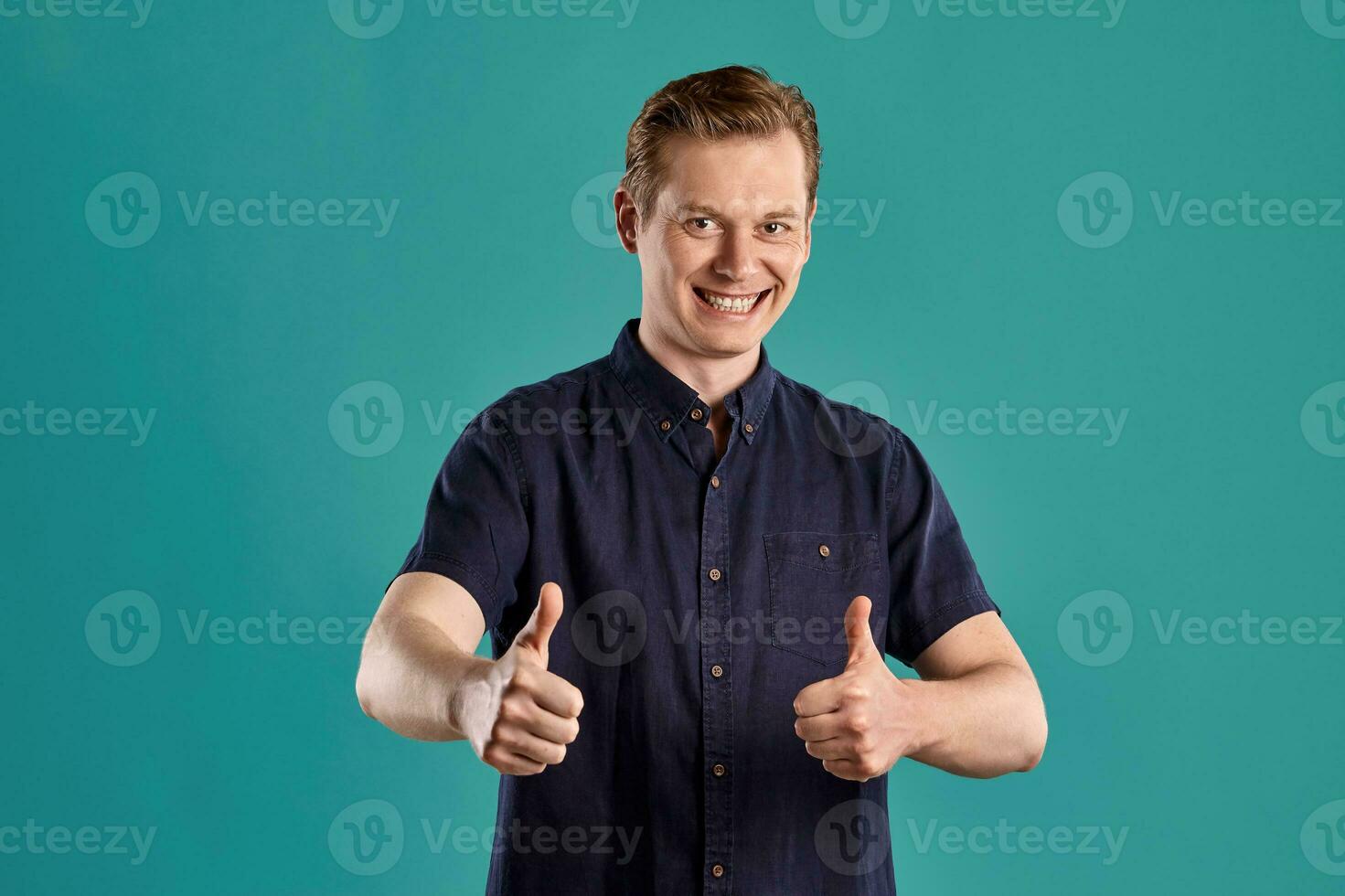 Close-up portrait of a ginger guy in navy t-shirt posing on blue background. Sincere emotions. photo