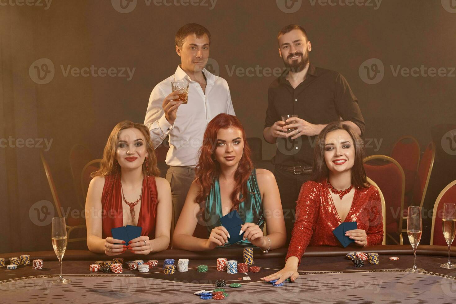 Group of a young wealthy friends are playing poker at a casino. photo