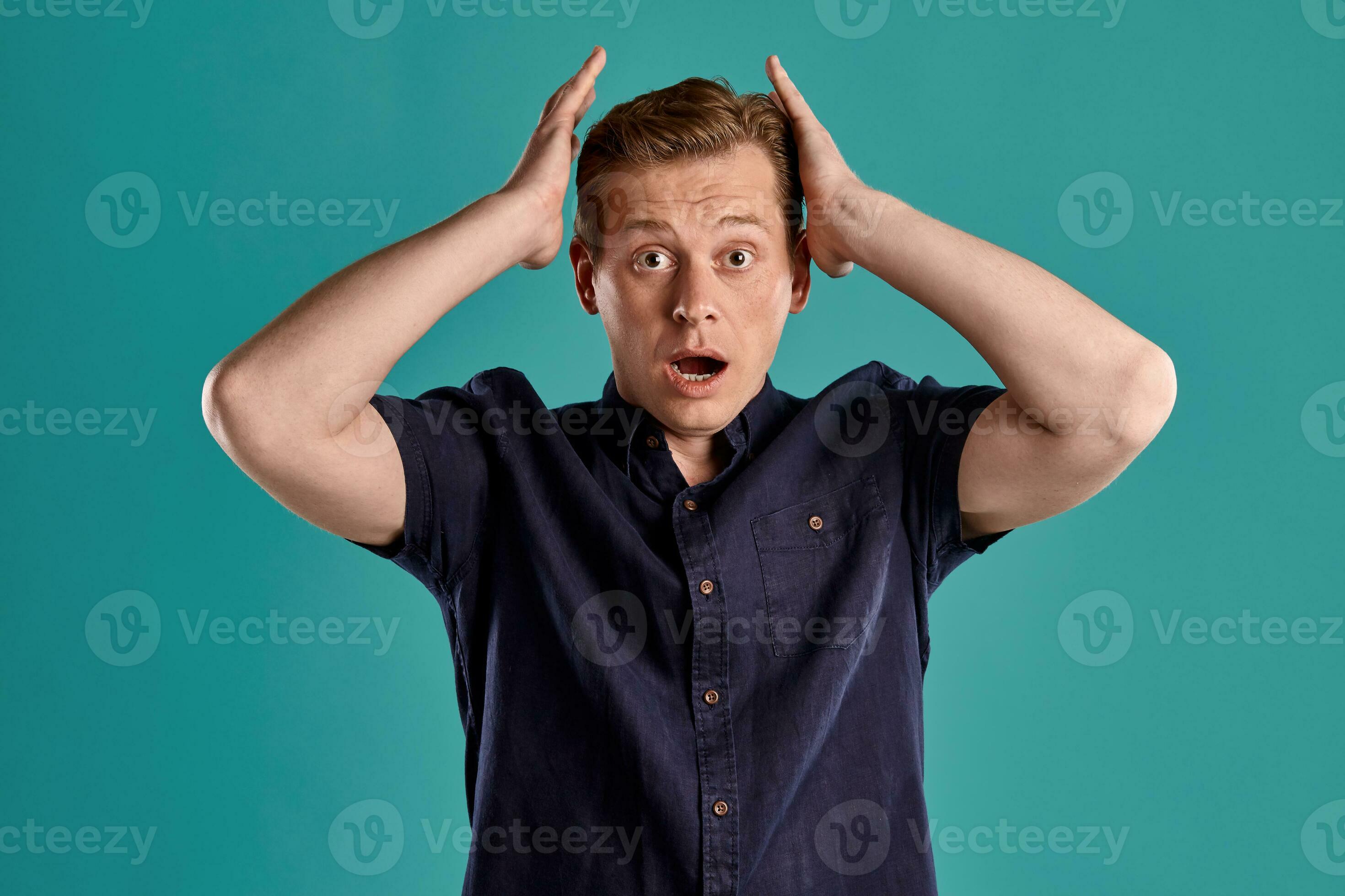 Closeup portrait of a ginger guy in navy tshirt posing on blue