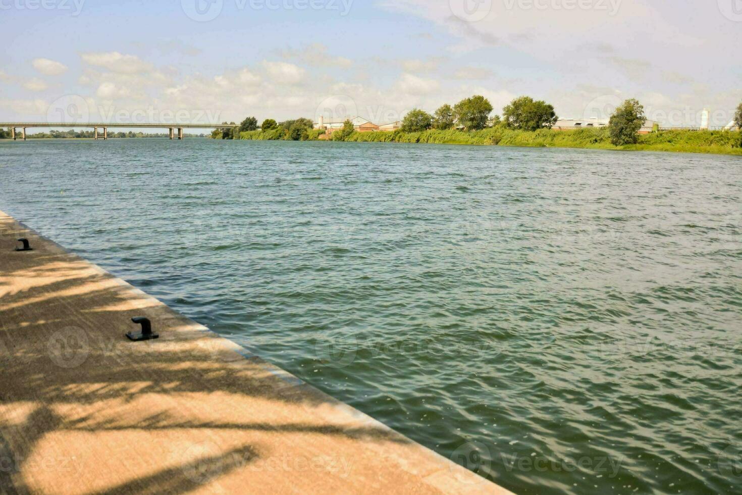 un muelle con un cuerpo de agua y un puente en el antecedentes foto