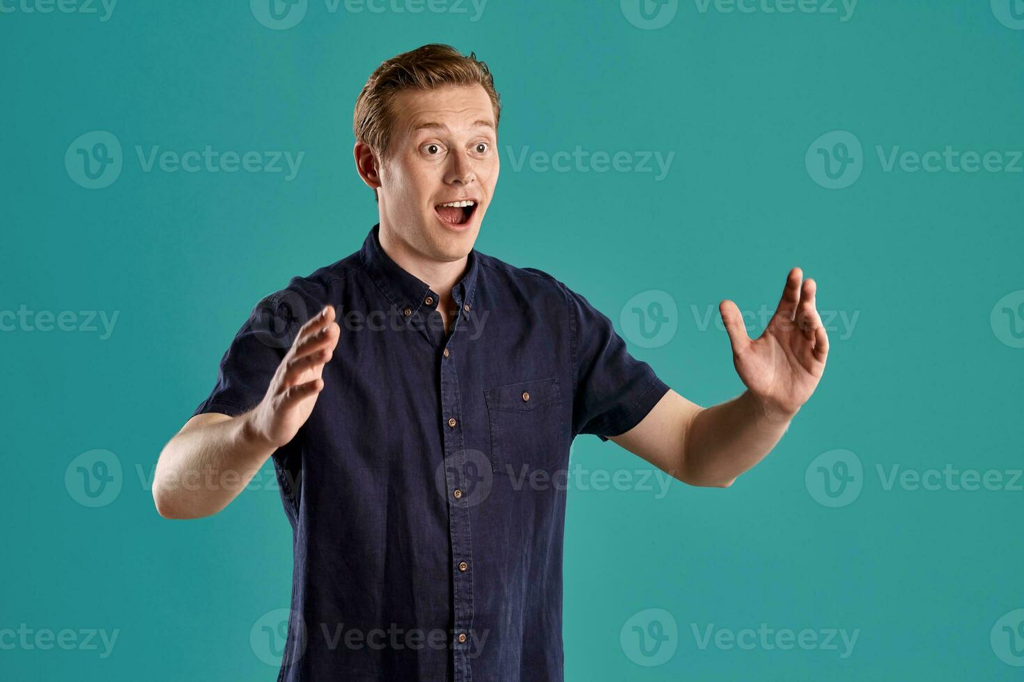 de cerca retrato de un jengibre chico en Armada camiseta posando en azul antecedentes. sincero emociones foto