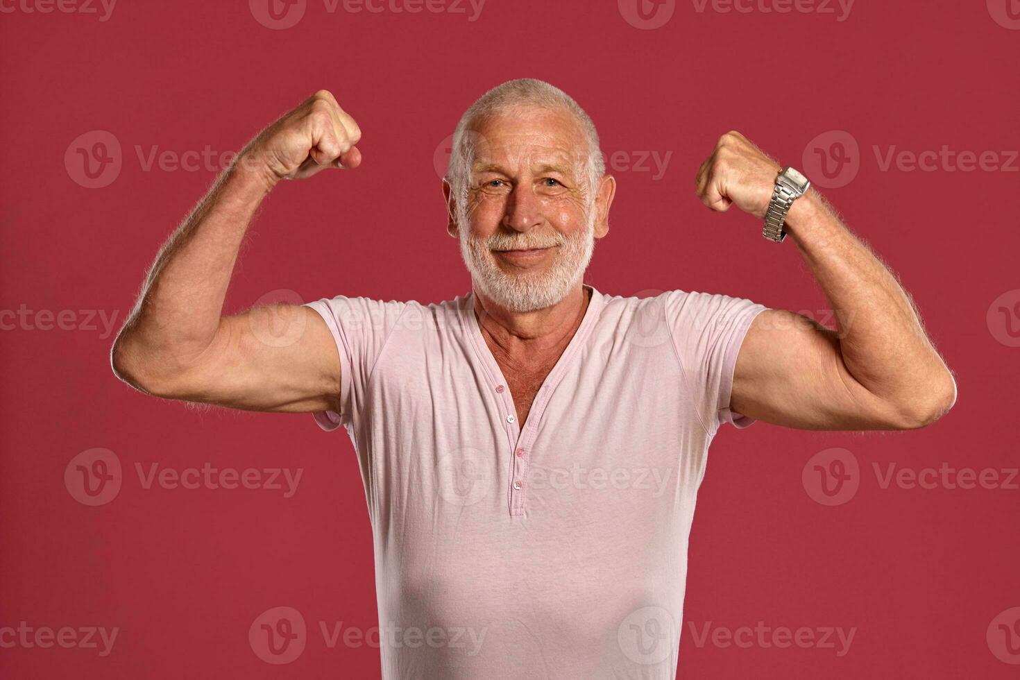 Handsome mature man posing against a pink studio background. photo