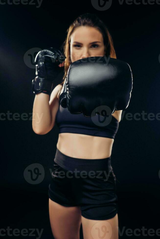 Athletic woman in boxing gloves is practicing karate in studio. photo