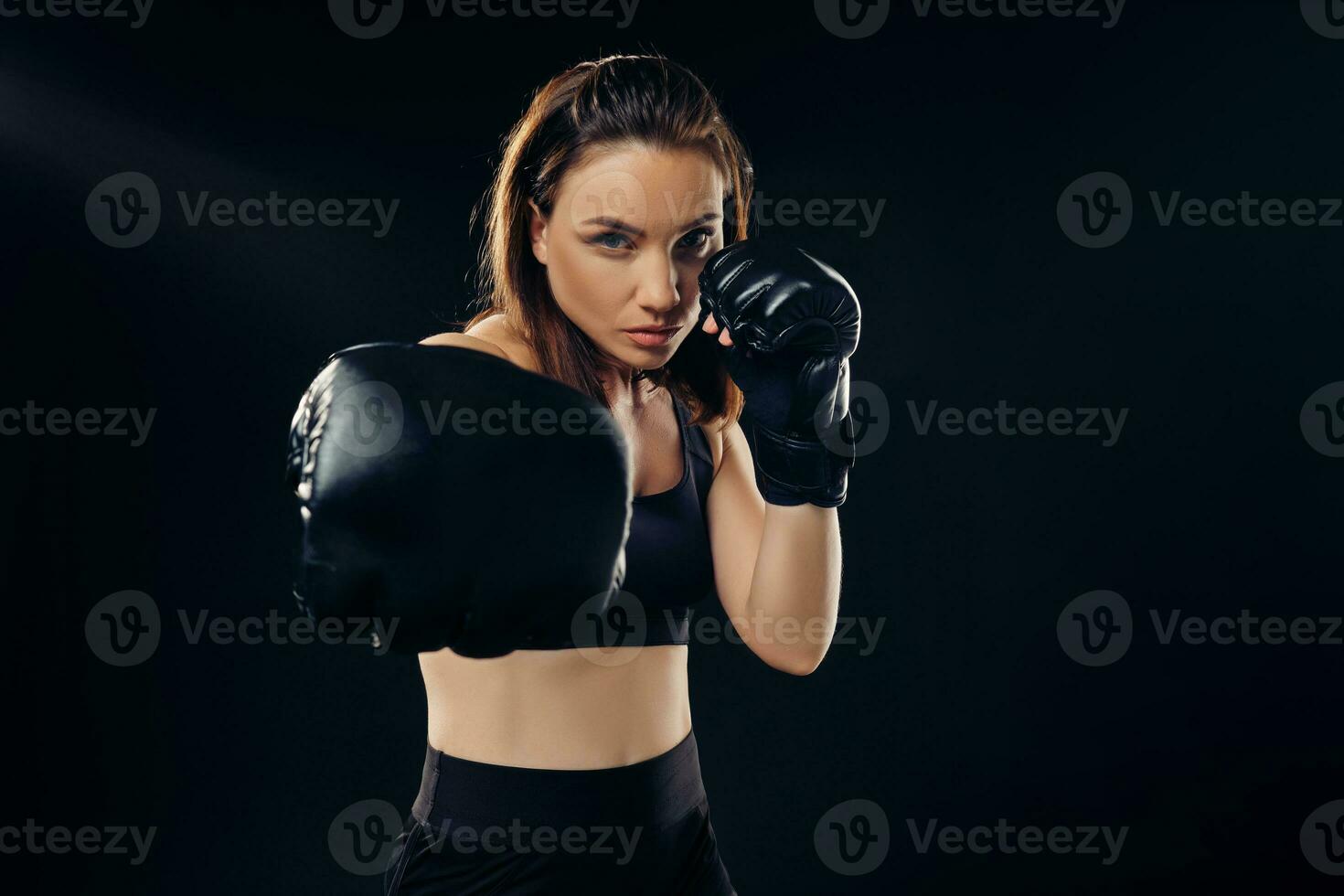 Athletic woman in boxing gloves is practicing karate in studio. photo