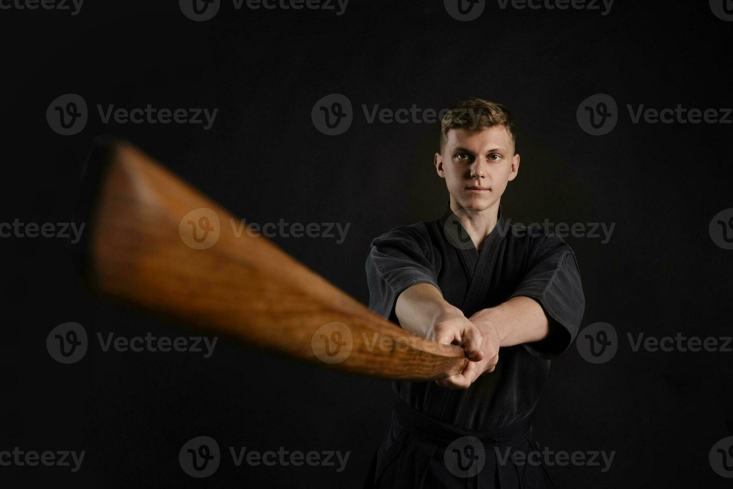 kendo gurú vistiendo en un tradicional japonés kimono es practicando marcial Arte con el shinai bambú espada en contra un negro estudio antecedentes. foto