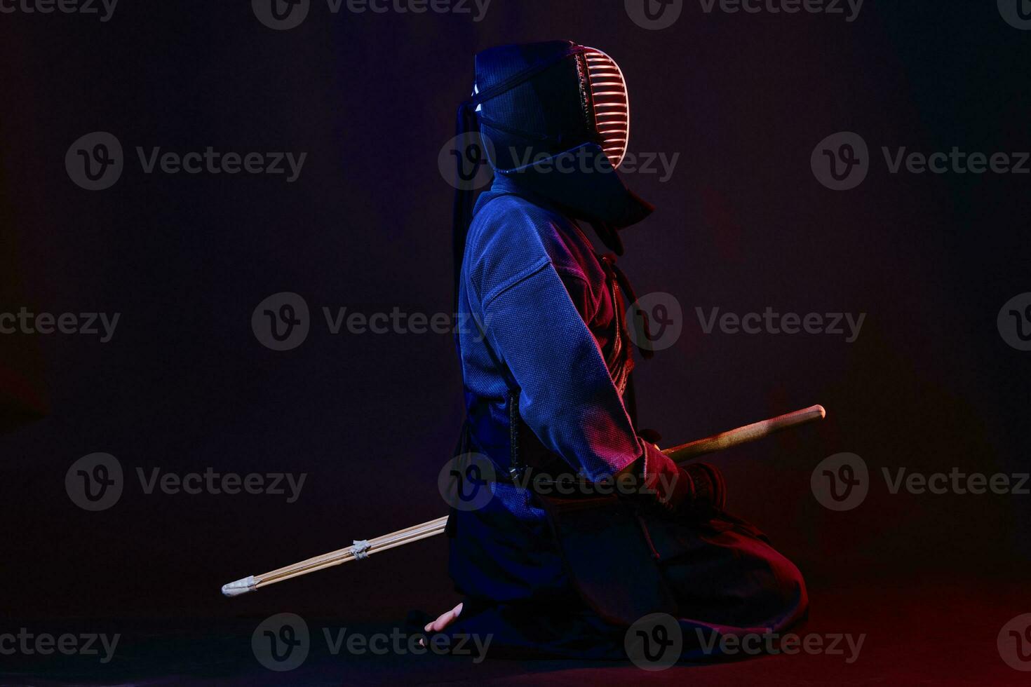 cerca arriba disparo, kendo combatiente vistiendo en un armadura, tradicional kimono, casco practicando marcial Arte con shinai bambú espada, negro antecedentes. foto