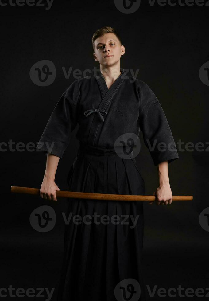 kendo gurú vistiendo en un tradicional japonés kimono es practicando marcial Arte con el shinai bambú espada en contra un negro estudio antecedentes. foto