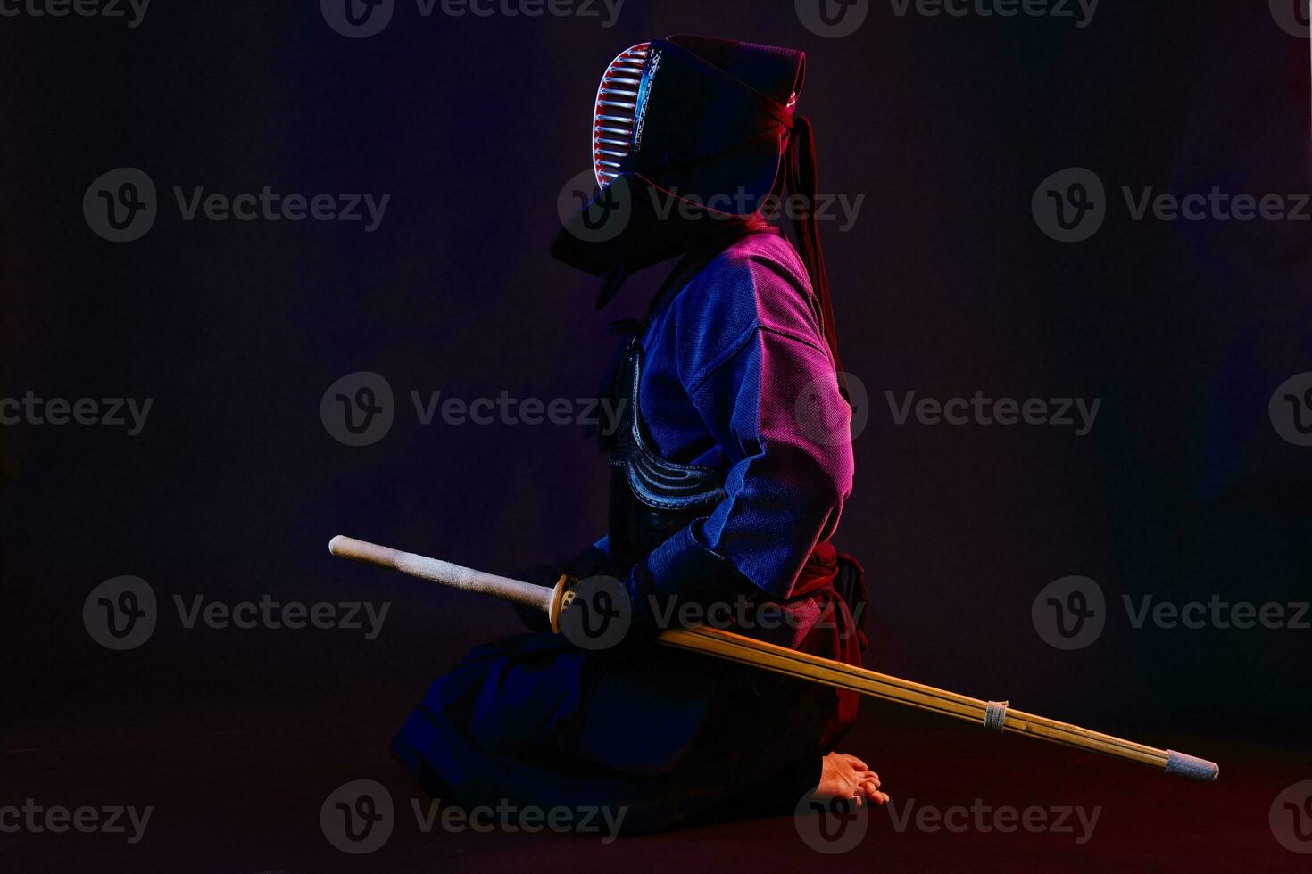 cerca arriba disparo, kendo combatiente vistiendo en un armadura, tradicional kimono, casco practicando marcial Arte con shinai bambú espada, negro antecedentes. foto