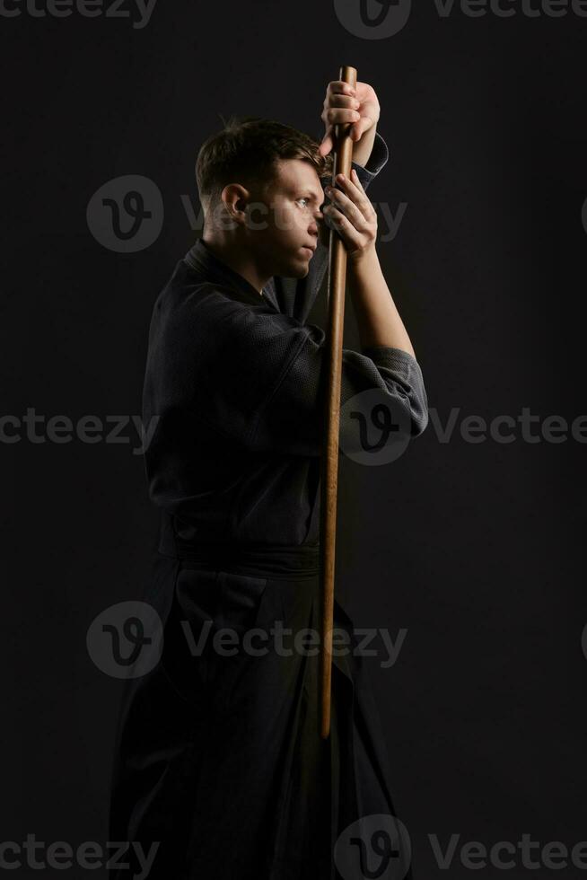 kendo gurú vistiendo en un tradicional japonés kimono es practicando marcial Arte con el shinai bambú espada en contra un negro estudio antecedentes. foto